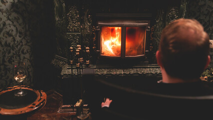 Warming up by the fire, cozy winter night in the cabin house by the fireplace, fireplace burns in...