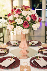 a table decorated with plates, bowls and a vase with flowers in the center