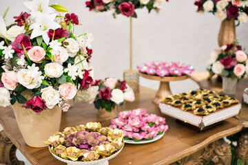a tray with sweets and vases with red and white flowers on top of a table