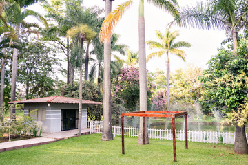 palm trees, a pergola in the garden and a house in the background