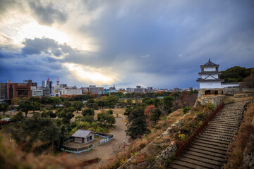 God rays break through storm clouds over Japanese castle in small city