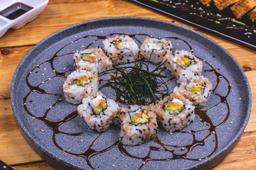 Delicioso plato de sushi empanizado bañado en salsa inglesa sobre una mesa