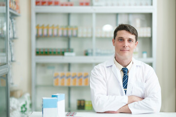 Male pharmacist working in modern pharmacy looking at camera.