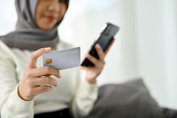 selective focus, A beautiful Muslim woman holding a credit card and using her smartphone
