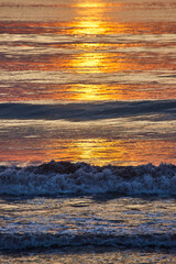 Detail vertical of crashing waves over east coast ocean with golden sunrise light casting light © Nicholas J. Klein