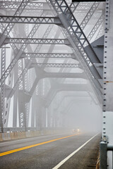Cars going down extremely foggy steel bridge from side