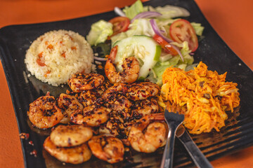 Deliciosos camarones adobados a la plancha servidos en un plato con ensalada y arroz 