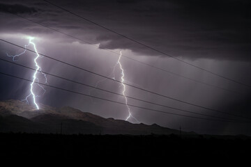 Lightning bolts strike mountains with power lines - obrazy, fototapety, plakaty
