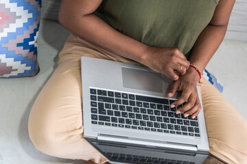 Unrecognizable woman working at home with a laptop on a floor. Writing an email.