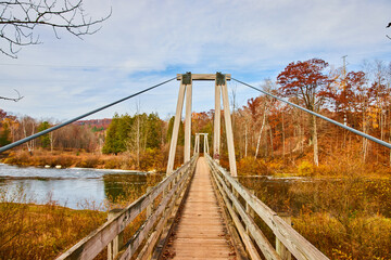 Walking down suspension bridge along river with fall foliage around