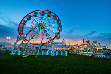 Blurred ferris wheel at American summer county fair during dusk