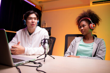Young African American woman and asian man a podcast interview and conversation together in studio,...