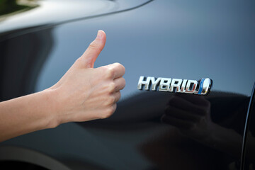 Purchaser hand showing thumb up sign at hybrid car new effective vehicle