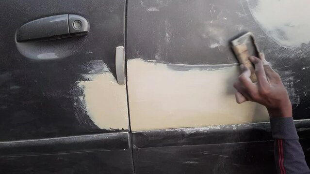 A Worker Rubbing Car Metal Lambi Putty On Car