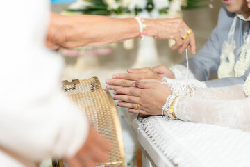 Sacred thread tied in a Thai wedding ceremony The hands of the bride and groom are tied with threads. Thai wedding culture with Oraporn