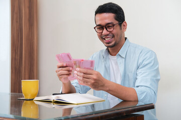 Adult Asian man smiling happy when counting money that he earn