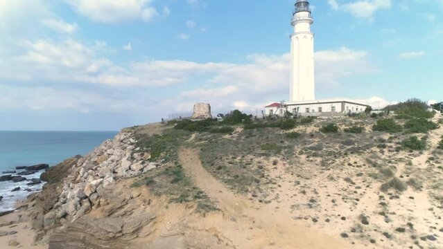 Aerial view flying forward past Trafalgar lighthouse in Los Canos de Meca Spain