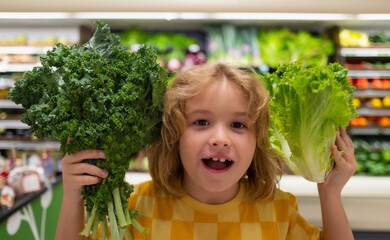 Child with lettuce chard vegetables. Little child choosing food in grocery store or a supermarket.
