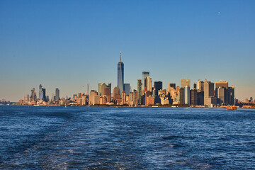 Naklejka premium Stunning southern Manhattan island from ferry with soft golden light