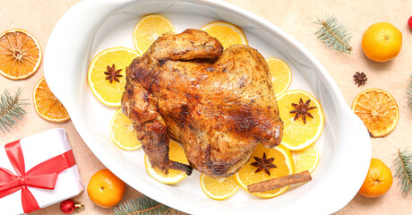 Baking dish with tasty roasted chicken, orange slices and Christmas gift on grunge background