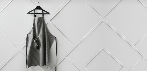 Clean apron hanging on grey wall with space fro text