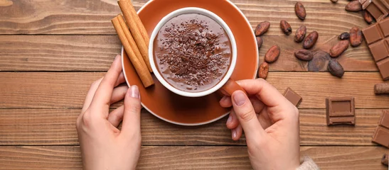 Foto op Canvas Female hands with cup of hot chocolate and cinnamon on wooden background © Pixel-Shot