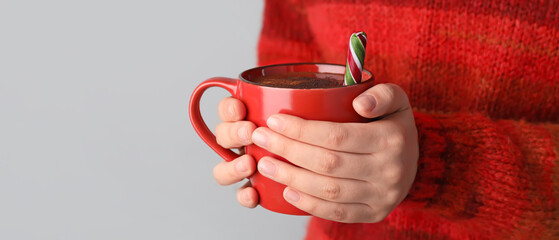 Woman with cup of hot chocolate on light background, closeup