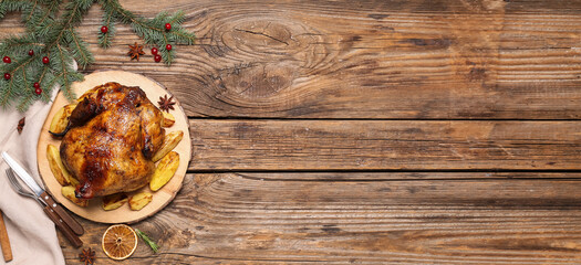 Tasty roasted chicken with potatoes and Christmas decorations on wooden background with space for text