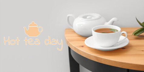 Cup of tasty beverage and teapot on table. Hot Tea Day