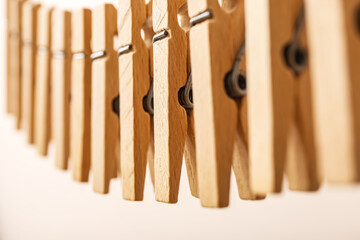 Wooden clothespins hanging on rope against color background, closeup
