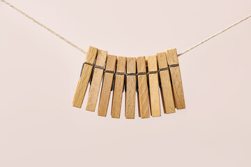 Wooden clothespins hanging on clothesline against color background