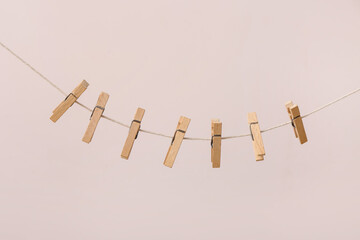 Wooden clothespins hanging on clothesline against color background