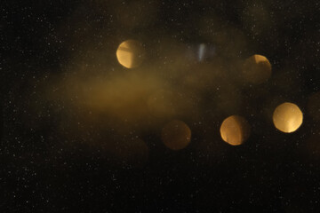 Black texture with white speckles and bokeh as background