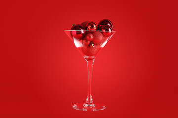 Glass with Christmas balls on red background