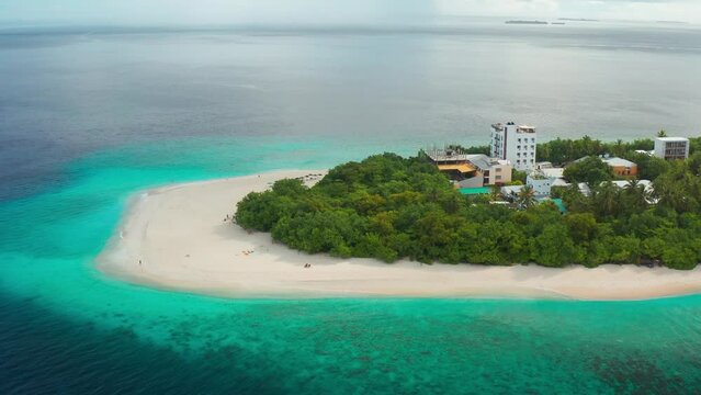 Local island Ukulhas with small hotels and white sand beach with palm and azure sea in Maldives. Aerial drone view.