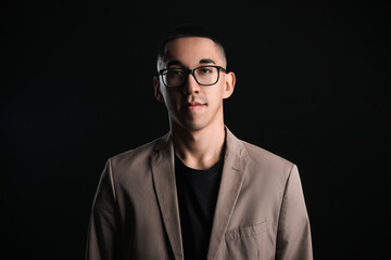 Portrait of young Asian man wearing eyeglasses on black background