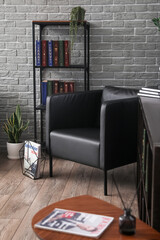 Bookshelf and armchair near grey brick wall in library