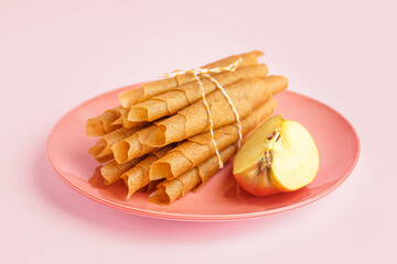 Plate with tasty apple pastilles on pink background
