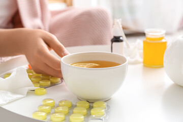 Woman with cup of lemon tea for sore throat at home, closeup