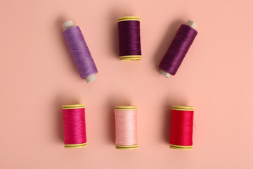 Colorful thread spools on pink background