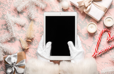 Santa Claus with tablet computer, Christmas decor and gifts on grunge background