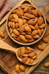 Board with bowl of almonds on wooden background