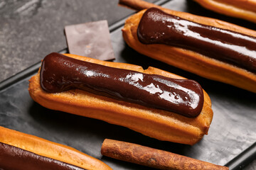 Board with tasty chocolate eclairs, closeup