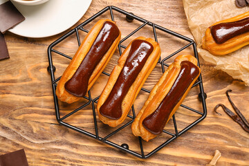Grid with delicious chocolate eclairs on wooden background