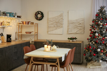 Interior of kitchen with glowing Christmas tree, counters and dining table