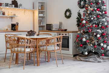 Interior of kitchen with Christmas trees, glowing lights and dining table