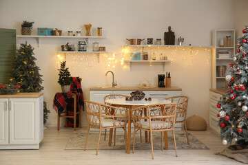 Interior of kitchen with glowing Christmas trees, shelves and dining table
