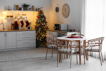 Interior of kitchen with glowing Christmas tree, counters and dining table