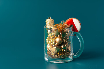 Glass with Christmas decorations on dark green background