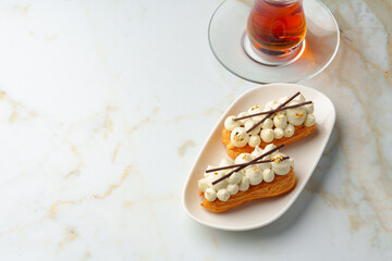 Two eclairs with white custard on whhite plate